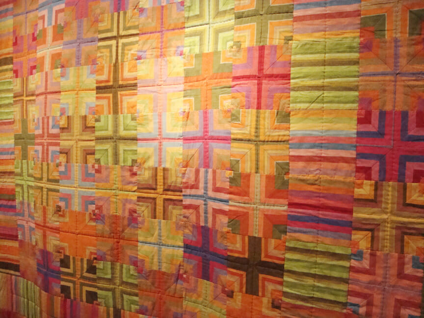 Autumn Crosses by Kaffe Fassett. The colors from this quilt were used to design the exhibit hall. Walls are painted shades of crushed berry and citrus.